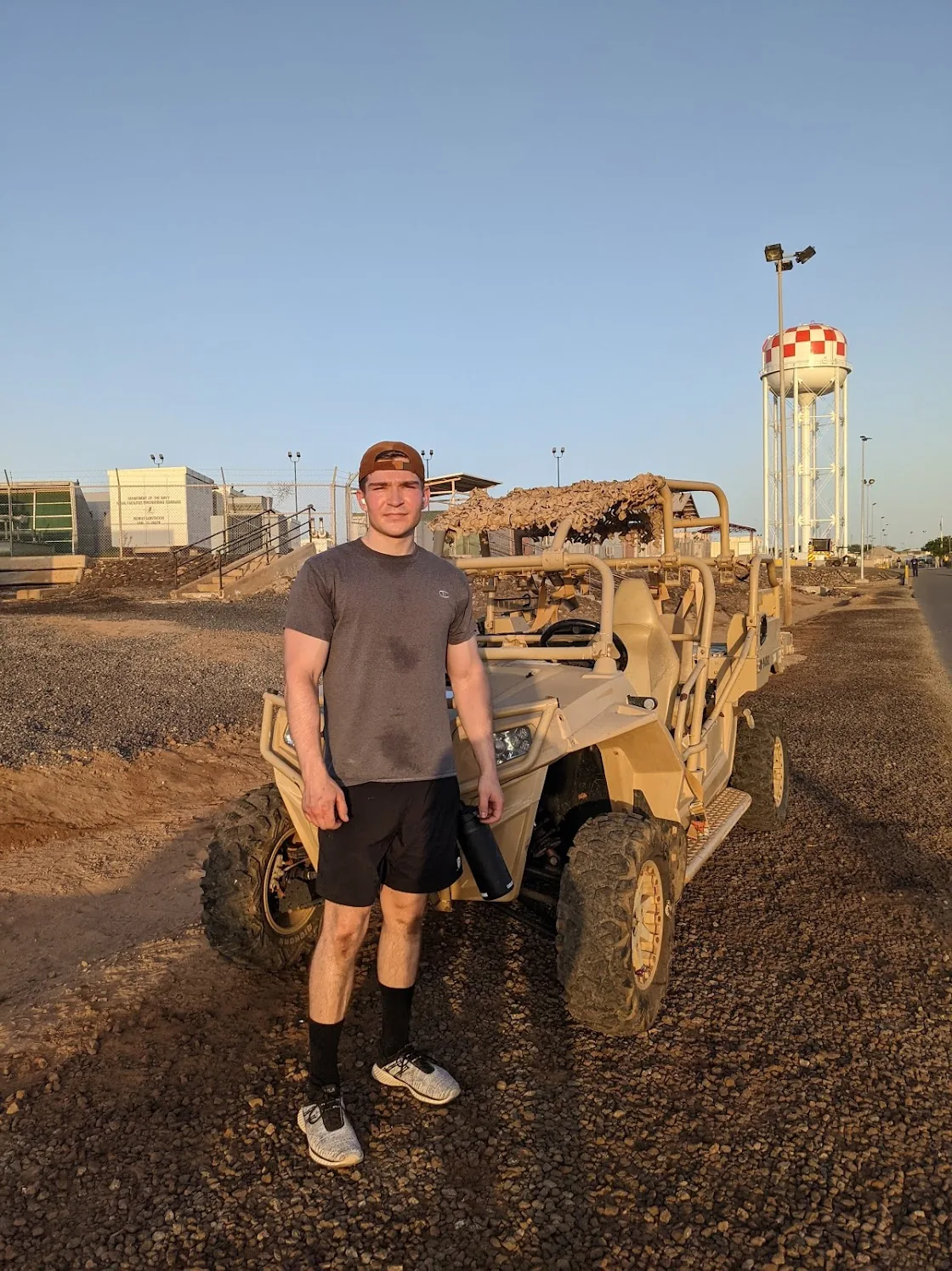 Kyler Yake on deployment, beside a tactical vehicle at dusk
