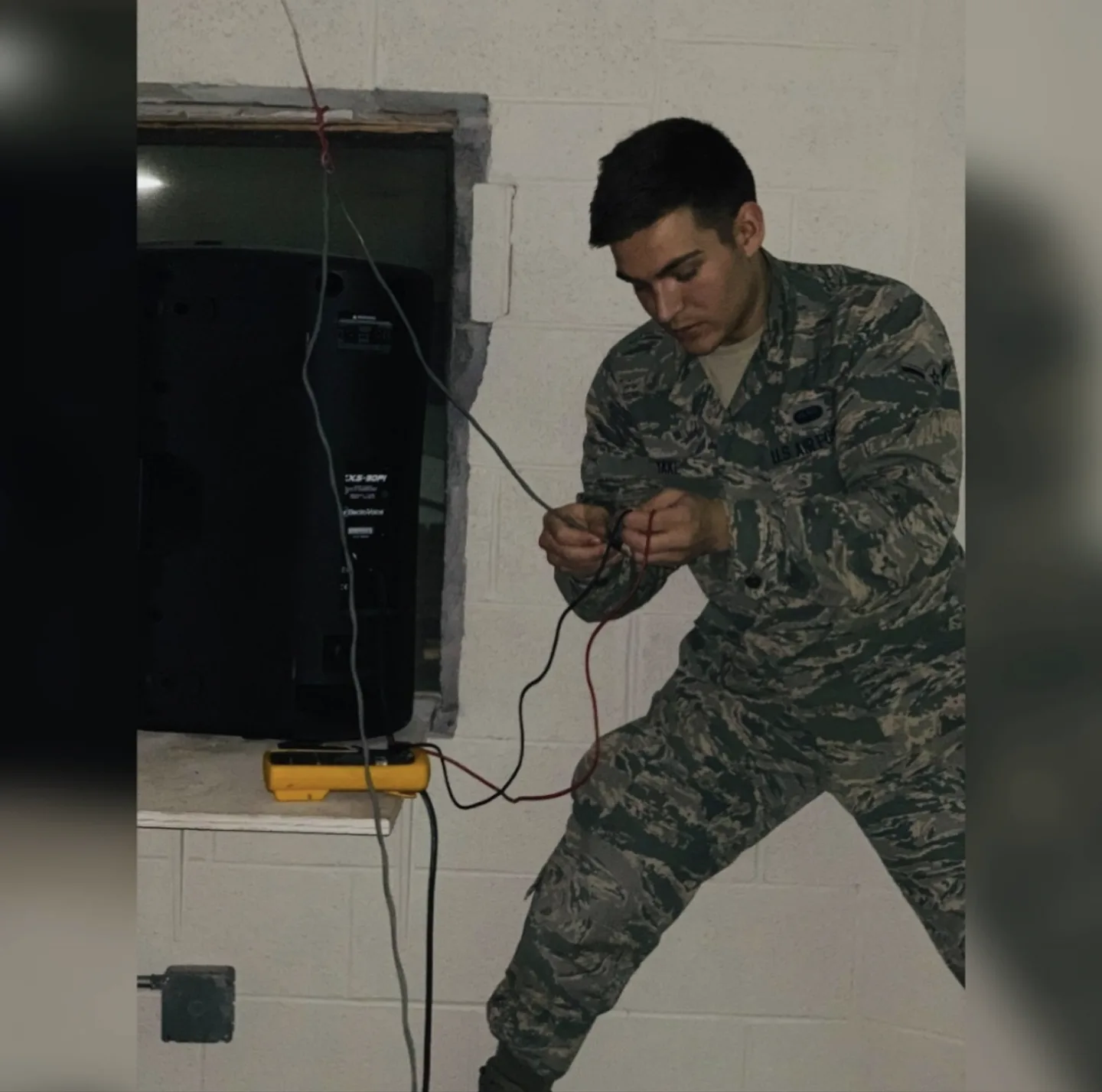 Kyler Yake in uniform, wiring a speaker on an Air Force base
